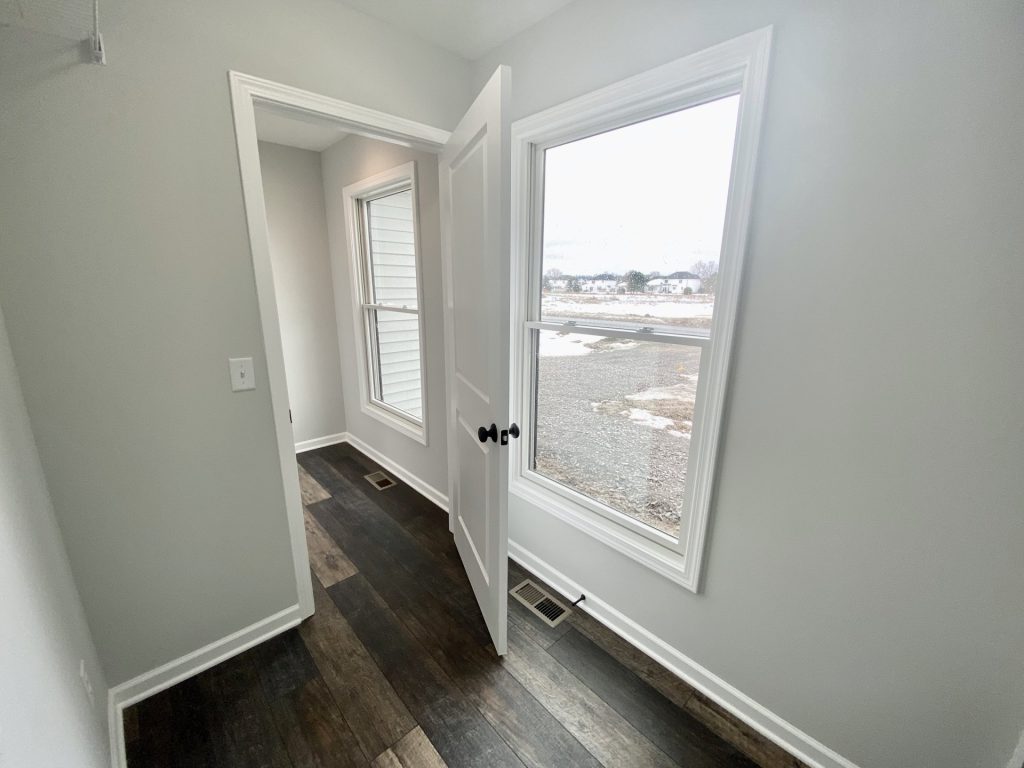 The Cooper I Mudroom with Tall Window, Wood-Look Flooring, White Trim & Open Door View