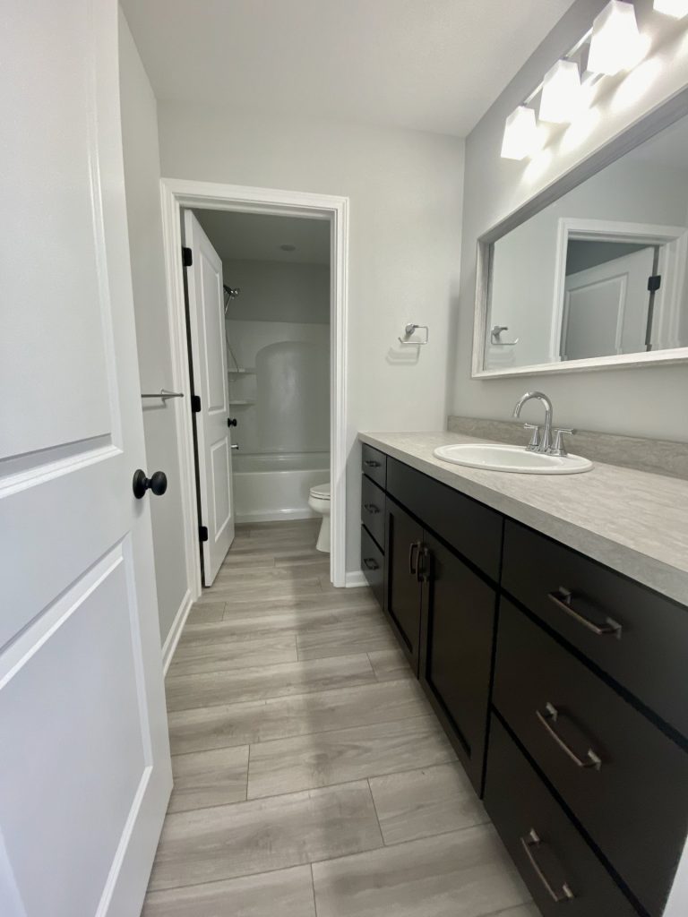 The Cooper I Full Bathroom with Dark Vanity, Light Countertop, Gray Tile Flooring, Large Mirror & Tub-Shower Combo