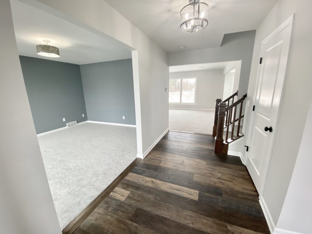 The Cooper I Front Entry Hall with Dark Wood-Look Flooring, Staircase, White Trim & Den View
