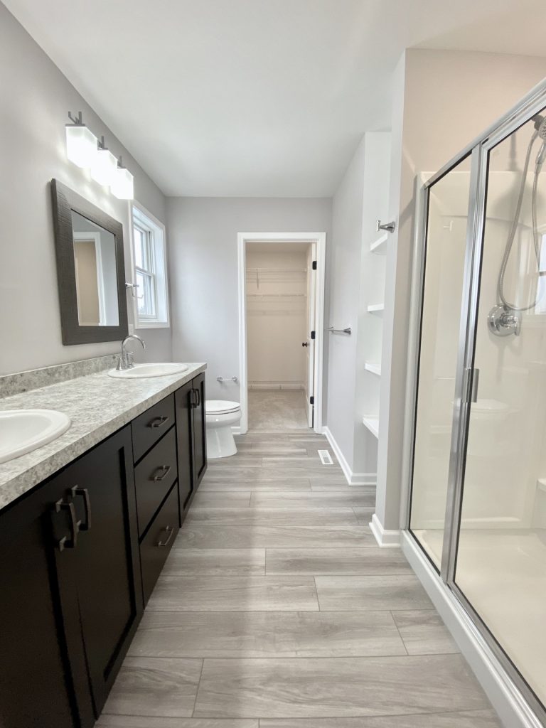 The Cooper I Primary Bathroom with Double Vanity, Glass Shower, Tile Flooring & Walk-In Closet View