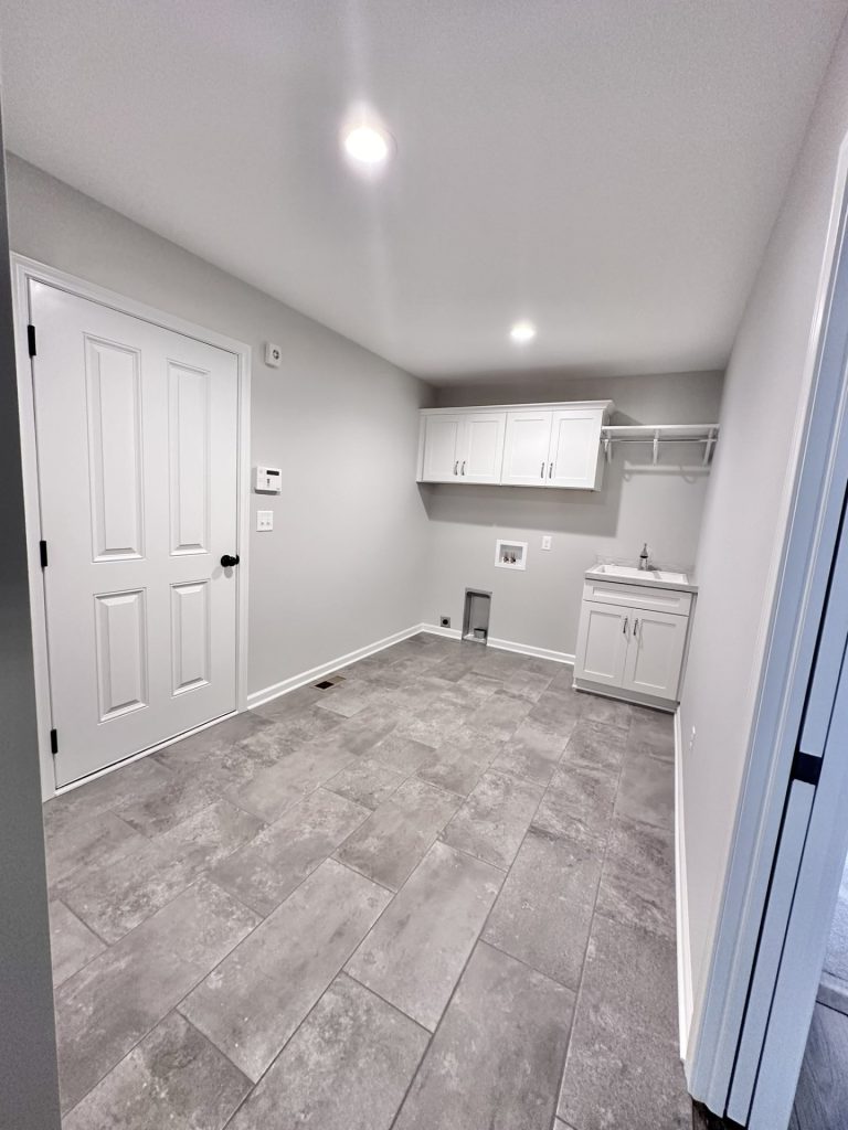 Golden-Laundry-Room-with-Gray-Tile-Flooring-White-Doors-and-Utility-Sink