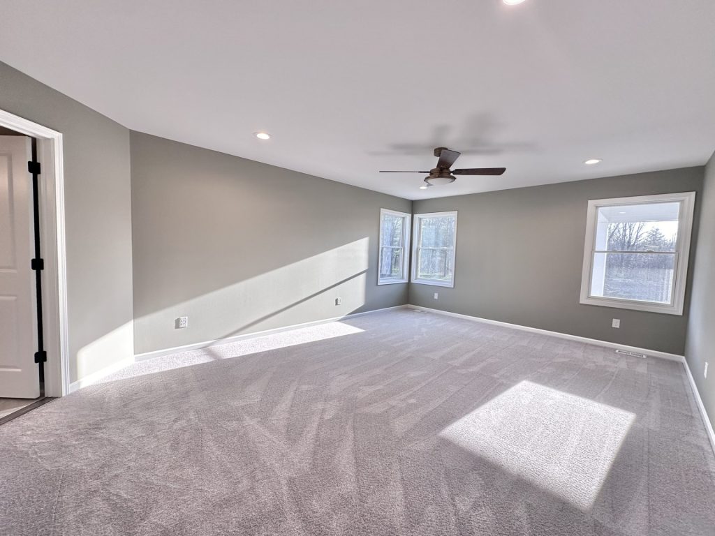 Golden-Primary-Bedroom-with-Soft-Gray-Carpet-Corner-Windows-and-Ceiling-Fan