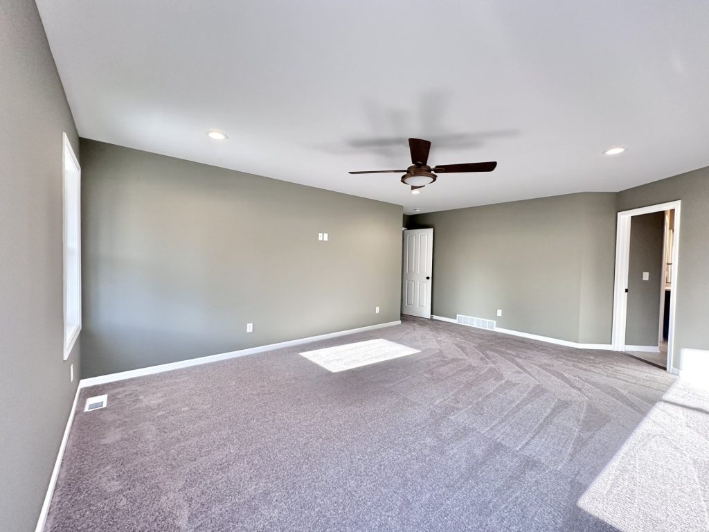 Golden-Primary-Bedroom-with-Soft-Gray-Carpet-Neutral-Walls-and-Ensuite-Bath-Entry