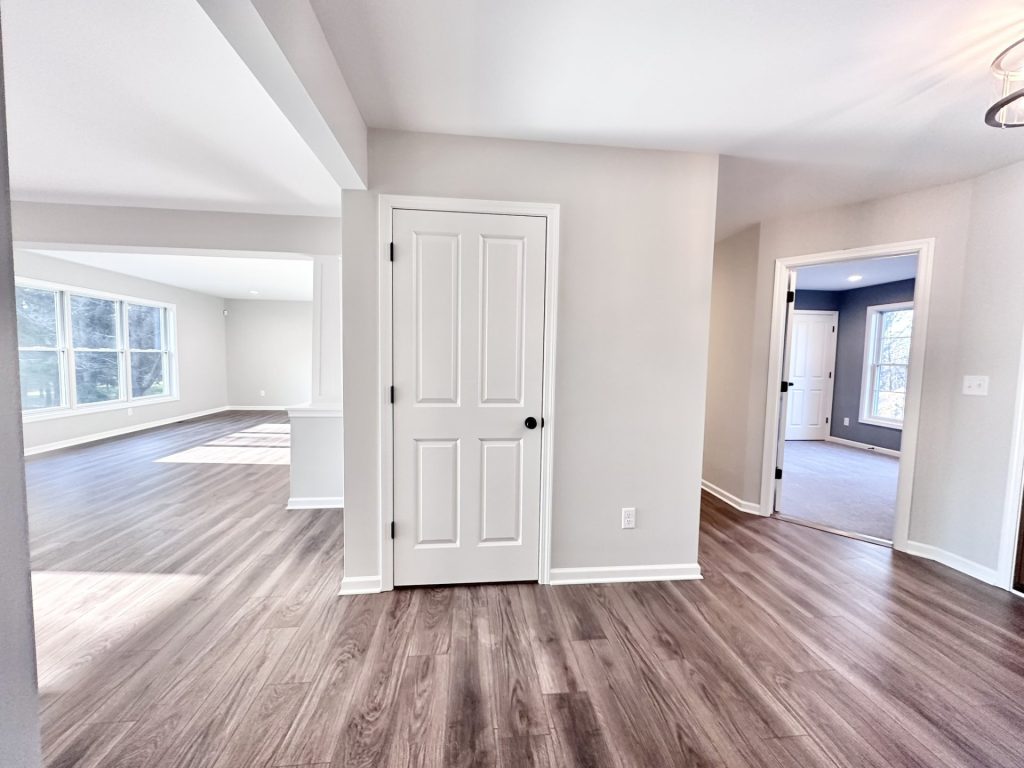 Golden-Interior-Hallway-with-Wood-Look-Flooring-White-Doors-and-Open-Living-Room-View
