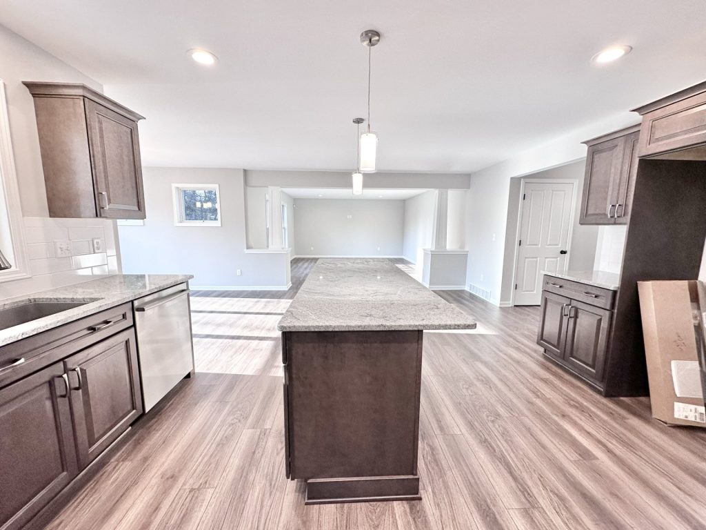 Golden-Kitchen-with-Long-Center-Island-Dark-Cabinetry-and-Open-Great-Room-View