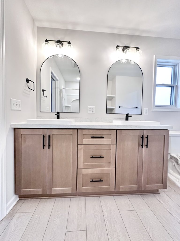 Cooper-Primary-Bath-Double-Vanity-Arched-Mirrors-Wood-Tone-Cabinetry-Black-Fixtures