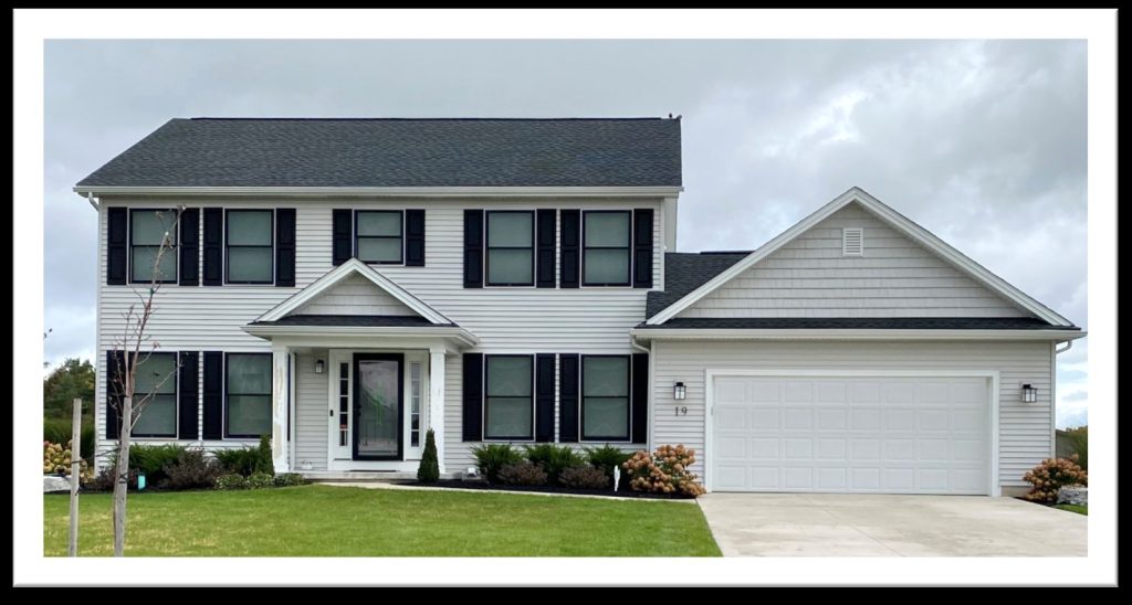 Two-story colonial home exterior with cream siding, black shutters, a covered entry portico, and attached two-car garage